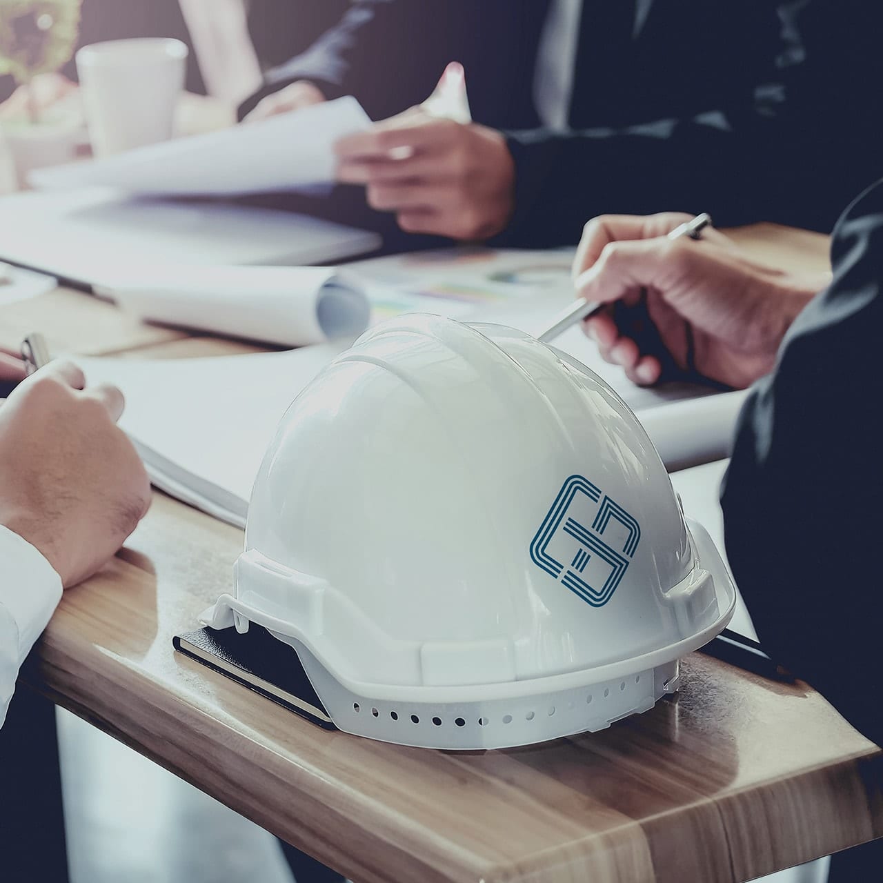 A branded hard hat sat on a table during a strategic construction planning meeting